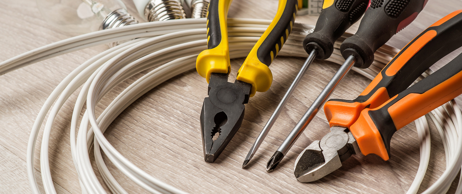 set of electrician tools, a coil of wire and equipment in backgr