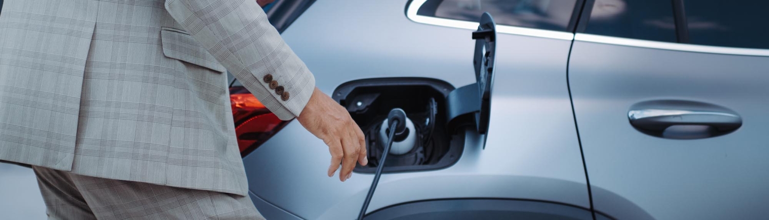Side view of a man charging an electric car