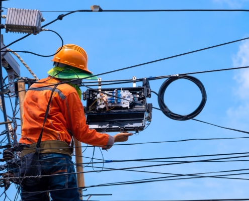 Side view of an electrical professional working on pole hardware on a sunny day