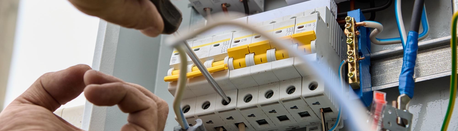 Worm's eye view of a professional fastening circuit breakers to DIN rail of electrical panel unit