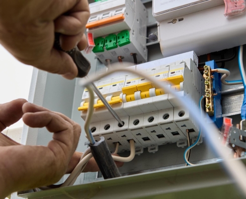 Worm's eye view of a professional fastening circuit breakers to DIN rail of electrical panel unit